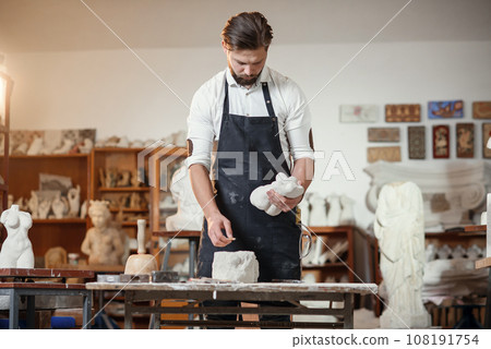 Bearded sculptor measures stone woman torso to make copy of it from limestone at creative studio. 108191754