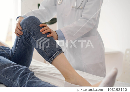Doctor and patient are at the usual medical inspection in the clinic. Therapist examines a young woman's knee. Medicine concept Doctor and patient are at the usual medical inspection in the clinic. Therapist examines a young woman's knee. Medicine concept 108192130