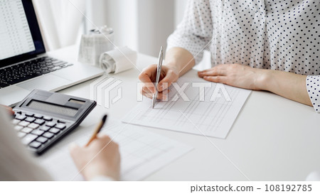 Two accountants using a laptop computer and calculator for counting taxes at white desk in office. Teamwork in business audit and finance 108192785