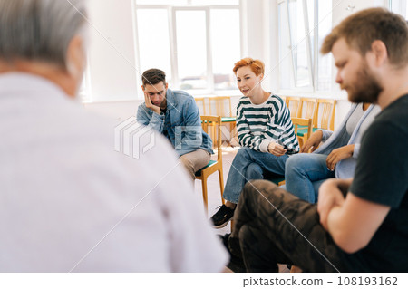 Back view of young pretty woman sharing problem sitting in circle during group therapy session. Concept of mental health, psychotherapy, depression, social issues, support, assistant. 108193162