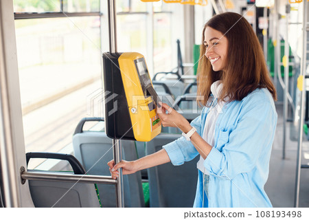 Young woman pays by bank card for the public transport in the tram or subway. Young woman pays by bank card for the public transport in the tram or subway. 108193498