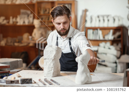 Bearded sculptor measures stone woman torso to make copy of it from limestone at creative studio. 108193762