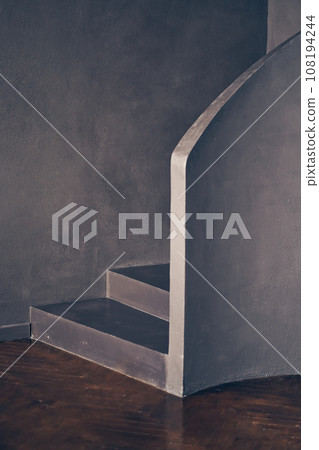 A modern black curved staircase indoors, a staircase made of black stone, a symbol of modern life. With space to copy. High quality photo A modern black curved staircase indoors, a staircase made of black stone, a symbol of modern life. With space to copy. High quality photo 108194244