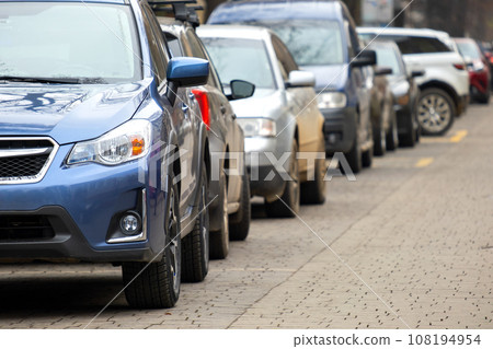 Cars parked in a row on a city street side. 108194954