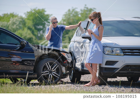 Angry woman and man drivers of heavily damaged vehicles calling insurance service for help in car crash accident on street side. Road safety concept Angry woman and man drivers of heavily damaged vehicles calling insurance service for help in car crash accident on street side. Road safety concept 108195015