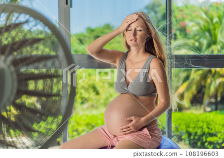 A pregnant woman seeks relief from an abnormal heatwave by using a fan, ensuring her comfort and well-being during sweltering conditions A pregnant woman seeks relief from an abnormal heatwave by using a fan, ensuring her comfort and well-being during sweltering conditions 108196603