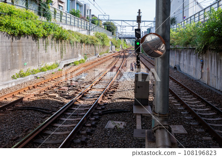 Straight train tracks seen from the end of a train station platform 108196823