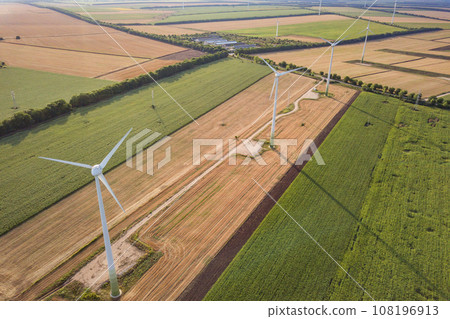 Aerial view of wind turbine generators in field producing clean ecological electricity. Aerial view of wind turbine generators in field producing clean ecological electricity. 108196913