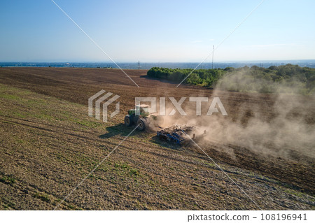 Aerial view of tractor plowing agriculural farm field preparing soil for seeding in summer 108196941