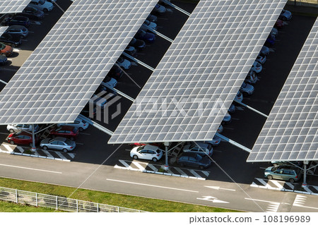 Aerial view of solar panels installed as shade roof over parking lot with parked cars for effective generation of clean electricity. Photovoltaic technology integrated in urban infrastructure 108196989