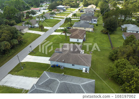 Aerial view of small town America suburban landscape with private homes between green palm trees in Florida quiet residential area Aerial view of small town America suburban landscape with private homes between green palm trees in Florida quiet residential area 108197002