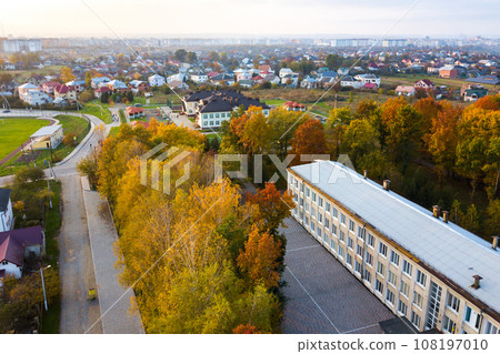 Aerial view of school, college or kindergarten building with big yard among autumn trees on rural landscape background Aerial view of school, college or kindergarten building with big yard among autumn trees on rural landscape background 108197010