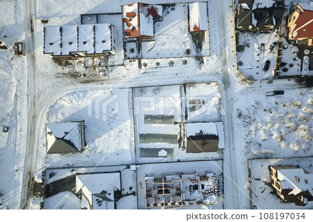 Aerial view of private homes with snow covered roofs in rural suburbs town area in cold winter Aerial view of private homes with snow covered roofs in rural suburbs town area in cold winter 108197034