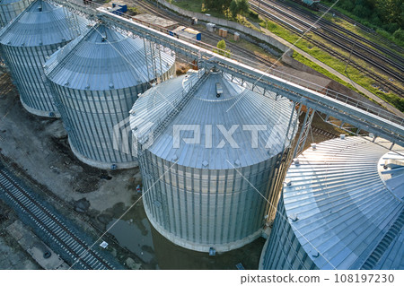 Aerial view of industrial ventilated silos for long term storage of grain and oilseed. Metal elevator for wheat drying in agricultural zone Aerial view of industrial ventilated silos for long term storage of grain and oilseed. Metal elevator for wheat drying in agricultural zone 108197230
