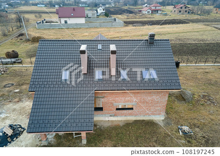 Aerial view of house roof top covered with ceramic shingles. Tiled covering of building under construction 108197245