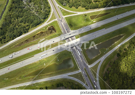 Aerial view of freeway overpass junction with fast moving traffic cars and trucks. Interstate transportation infrastructure in USA Aerial view of freeway overpass junction with fast moving traffic cars and trucks. Interstate transportation infrastructure in USA 108197272