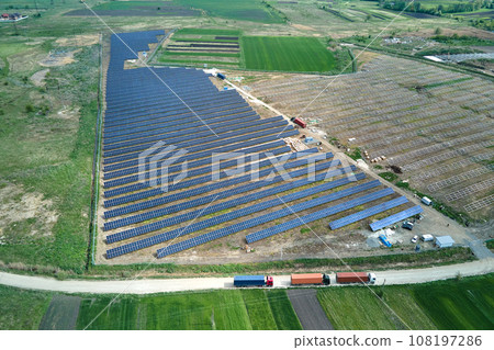 Aerial view of electrical power plant under construction with truck delivering assembly parts for solar panels on metal frame for producing electric energy. Development of renewable electricity Aerial view of electrical power plant under construction with truck delivering assembly parts for solar panels on metal frame for producing electric energy. Development of renewable electricity 108197286