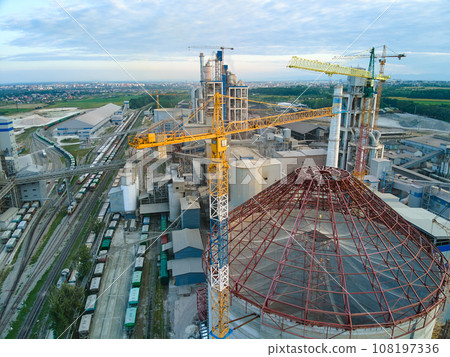 Aerial view of cement factory under construction with high concrete plant structure and tower cranes at industrial production area. Manufacture and global industry concept. 108197336