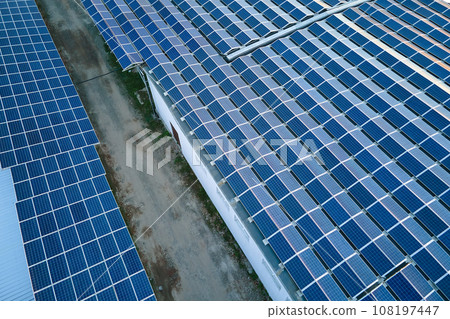 Aerial view of blue photovoltaic solar panels mounted on industrial building roof for producing green ecological electricity. Production of sustainable energy concept 108197447
