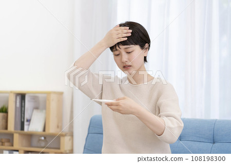 一位年輕女性測量體溫,感覺不適,發燒 一位年輕女性測量體溫,感覺不適,發燒 108198300