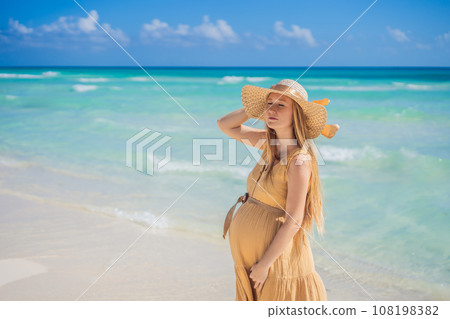Radiant and expecting, a pregnant woman stands on a pristine snow-white tropical beach, celebrating the miracle of life against a backdrop of natural beauty Radiant and expecting, a pregnant woman stands on a pristine snow-white tropical beach, celebrating the miracle of life against a backdrop of natural beauty 108198382