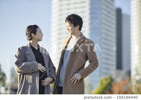 Pregnant woman and man walking hand in hand in the park Pregnant woman and man walking hand in hand in the park 108198440