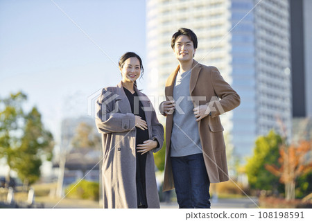 Pregnant woman and man walking hand in hand in the park Pregnant woman and man walking hand in hand in the park 108198591