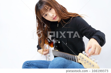 一位女士調音電吉他的圖片 108199373