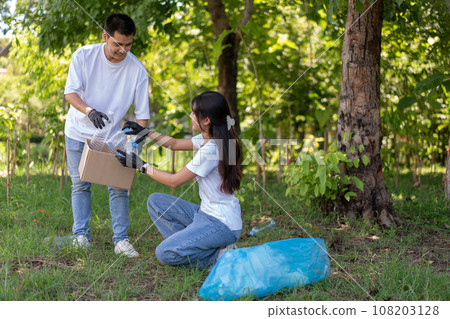 Happy young Asian students diverse volunteers with garbage bags cleaning area in the park, The concept of environmental conservation on world environment day, recycling, charity for sustainability. 108203128