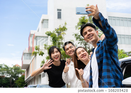 Group of happy young Asian students selfies and videos with smartphones together for vlog and social media on summer vacation. Concept of tourism and travel and road trip, friendship lifestyle. 108203428
