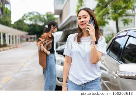 Asian women driver check for damage after a car accident before taking pictures and sending insurance. Online car accident insurance claim after submitting photos and evidence to an insurance company. Asian women driver check for damage after a car accident before taking pictures and sending insurance. Online car accident insurance claim after submitting photos and evidence to an insurance company. 108203618