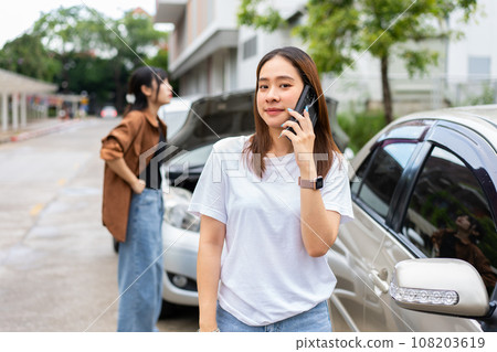 Asian women driver check for damage after a car accident before taking pictures and sending insurance. Online car accident insurance claim after submitting photos and evidence to an insurance company. 108203619