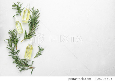 Fresh rosemary and bottles of essential oil on white table, flat lay. Space for text 108204593