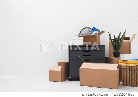 Cardboard boxes and packed belongings near white wall, space for text. Moving day Cardboard boxes and packed belongings near white wall, space for text. Moving day 108204633