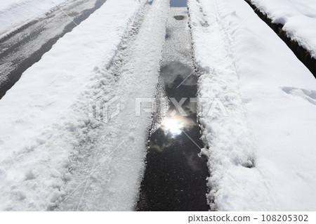 陽光反射在雪路上的車轍中融化的雪水坑里 108205302