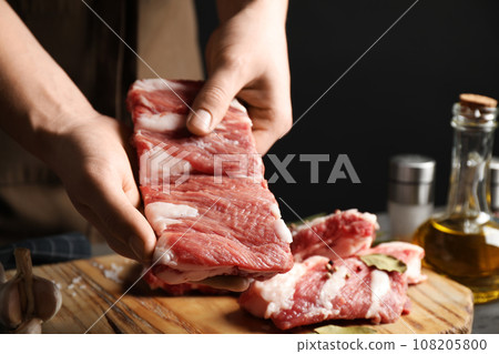 Man holding raw ribs at table, closeup Man holding raw ribs at table, closeup 108205800