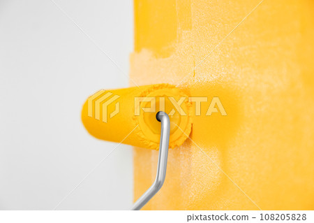 Painting white wall with yellow dye, closeup. Interior renovation 108205828