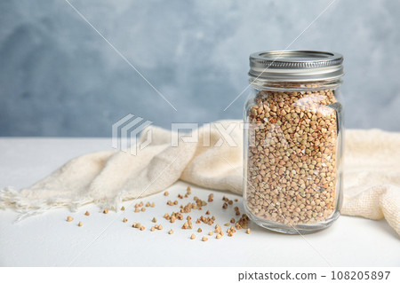 Jar with green buckwheat on white table. Space for text Jar with green buckwheat on white table. Space for text 108205897