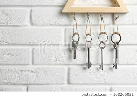 Wooden key holder on white brick wall indoors, closeup. Space for text 108206021