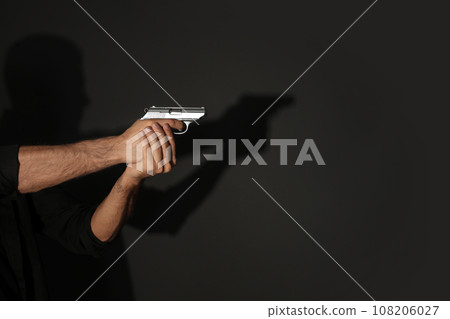 Professional killer with gun on black background, closeup 108206027