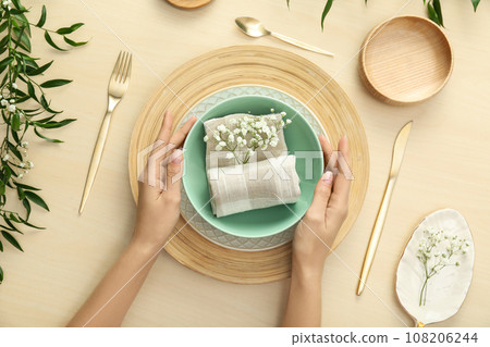 Woman setting table with flowers for festive dinner, top view 108206244