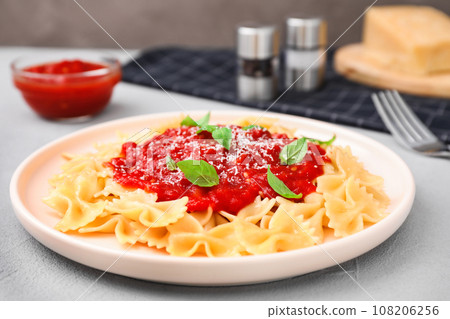 Tasty pasta with tomato sauce, basil and cheese on light grey table, closeup Tasty pasta with tomato sauce, basil and cheese on light grey table, closeup 108206256