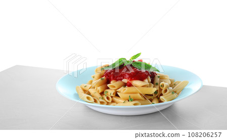 Tasty pasta with tomato sauce and basil on light grey table against white background 108206257