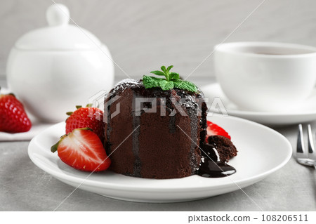 Delicious warm chocolate lava cake with mint and strawberries on table Delicious warm chocolate lava cake with mint and strawberries on table 108206511
