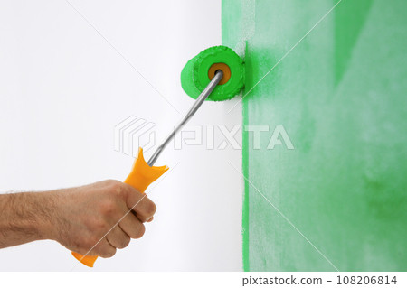 Man painting white wall with green dye, closeup. Interior renovation 108206814