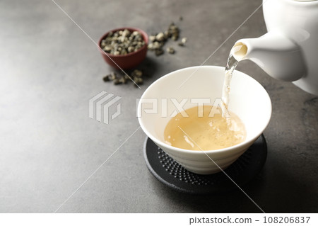 Pouring green tea into cup on grey table. Space for text 108206837