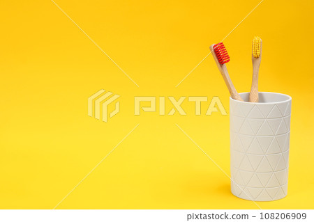 Toothbrushes made of bamboo in holder on yellow background. Space for text 108206909