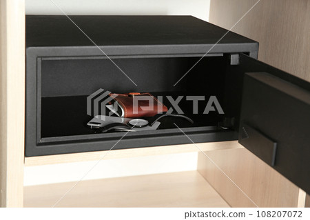 Open steel safe with wallet, watch and smartphone in wooden closet at hotel 108207072
