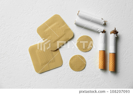 Nicotine patches and broken cigarettes on white background, flat lay Nicotine patches and broken cigarettes on white background, flat lay 108207093