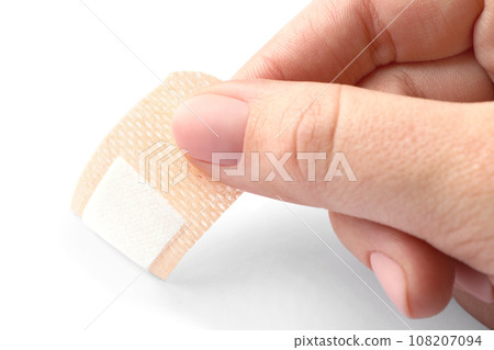 Woman putting sticking plaster on white background, closeup. First aid item Woman putting sticking plaster on white background, closeup. First aid item 108207094